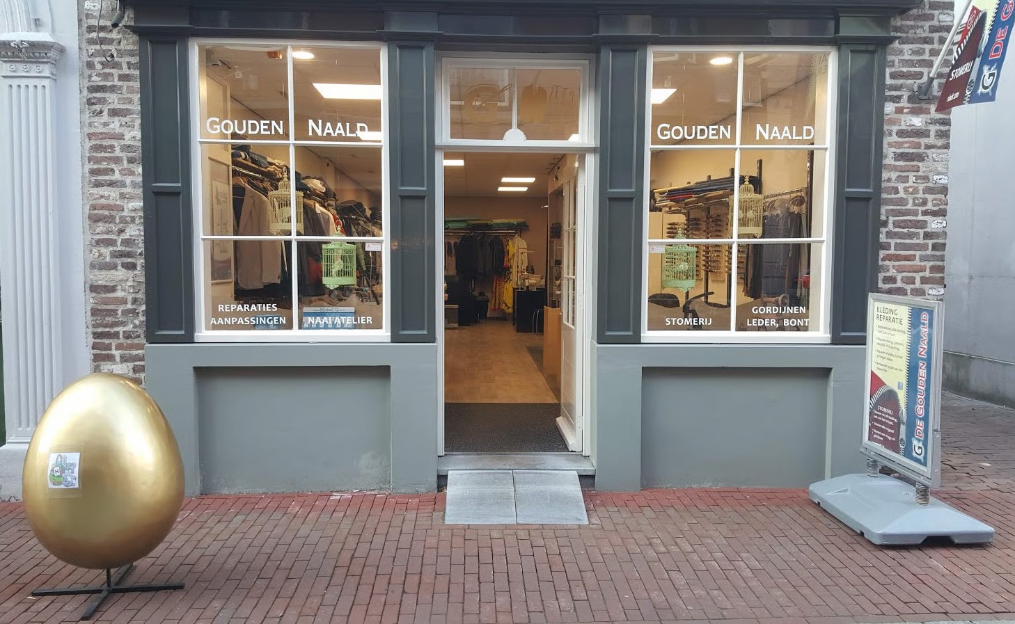 Voorgevel van De Gouden Naald aan de Maasstraat in Weert, met zicht door de open ingang naar de winkel
